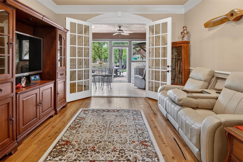 TV Room with beautiful wood flooring and double doors to enclosed patio with fireplace.