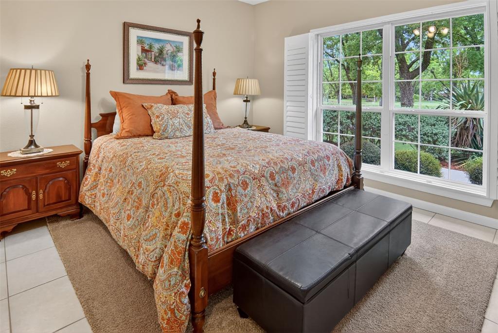 Guest bedroom with tile flooring and large windows with lovely view of back yard.