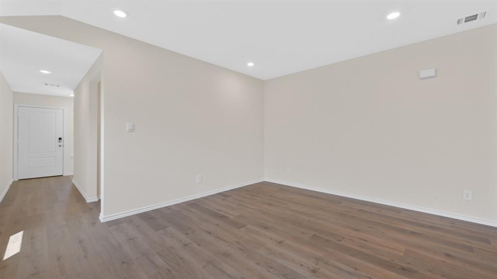 Spacious room featuring wood-finish flooring, recessed lighting, and neutral wall tones