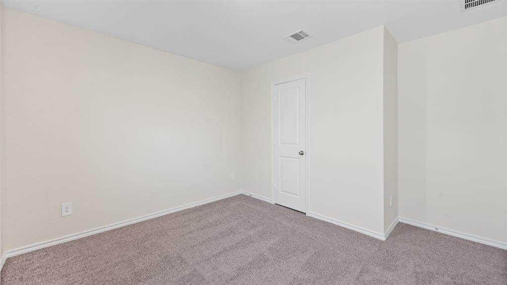 Carpeted room featuring light beige walls, white baseboards, and a white two-panel door with a round knob