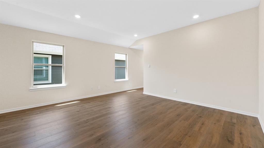 Spacious room featuring wood-finish flooring, recessed lighting, and multiple windows