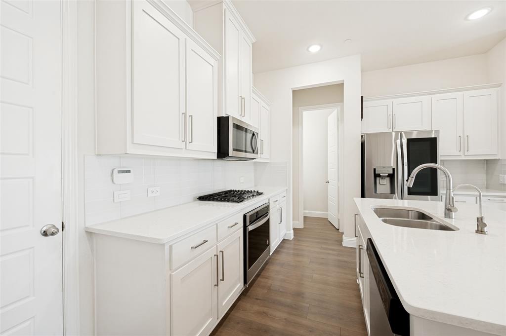 Modern kitchen featuring white shaker cabinetry, white subway tile backsplash, stainless steel appliances, and a double basin sink with a gooseneck faucet