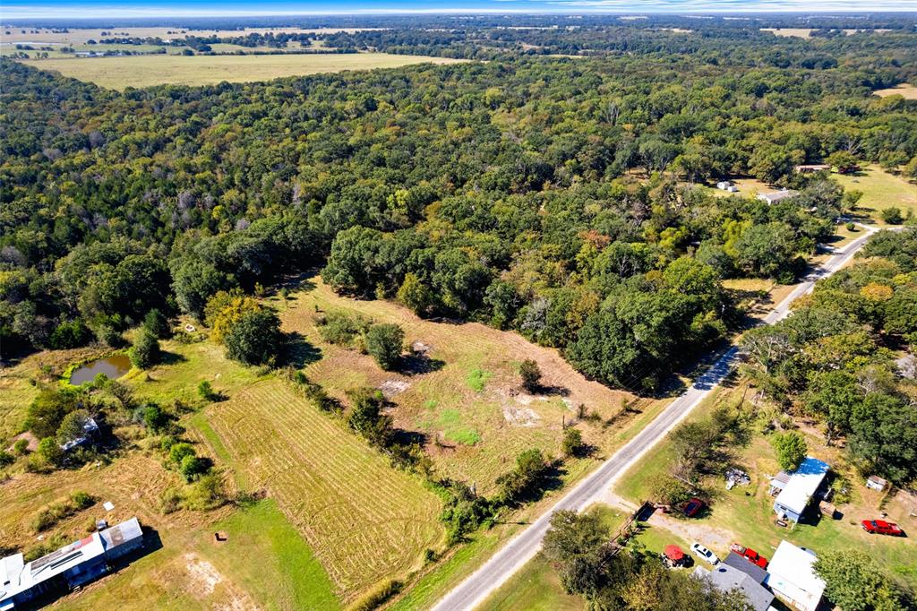 Expansive rural acreage featuring a natural pond, a cultivated field, and dense mature tree coverage