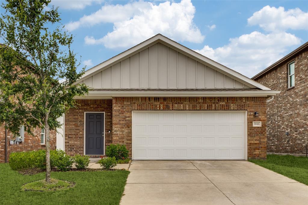 Brick facade residence featuring a two-car garage, a dark entry door, and a concrete driveway