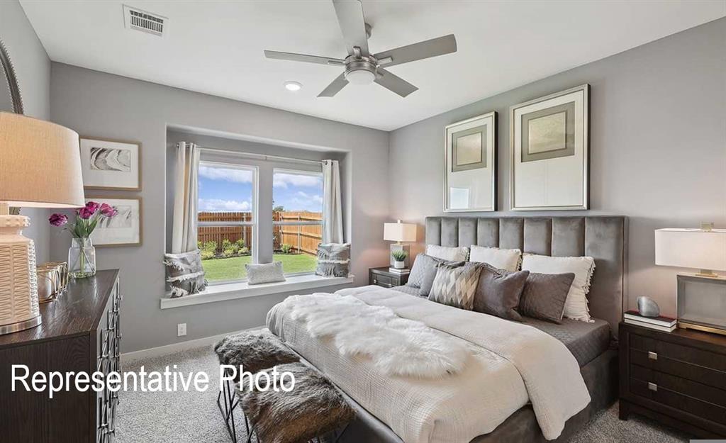 Spacious bedroom featuring plush carpeting, a large window with a built-in window seat, a contemporary ceiling fan, and ample natural light