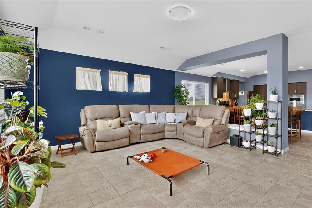 Spacious living area featuring tile flooring, a vaulted ceiling, and an open layout to the kitchen