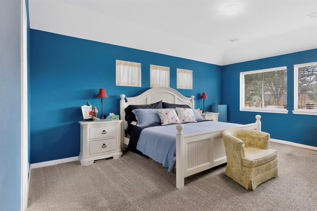 Bedroom featuring vaulted ceiling, two large windows, carpet flooring, and blue painted walls