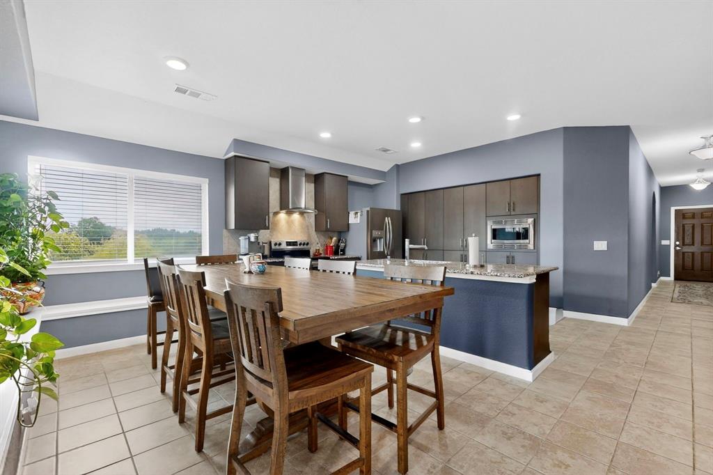 Open-concept kitchen and dining area featuring a built-in oven, stainless steel refrigerator, and recessed lighting Open-concept kitchen and dining area featuring a built-in oven, stainless steel refrigerator, and recessed lighting
