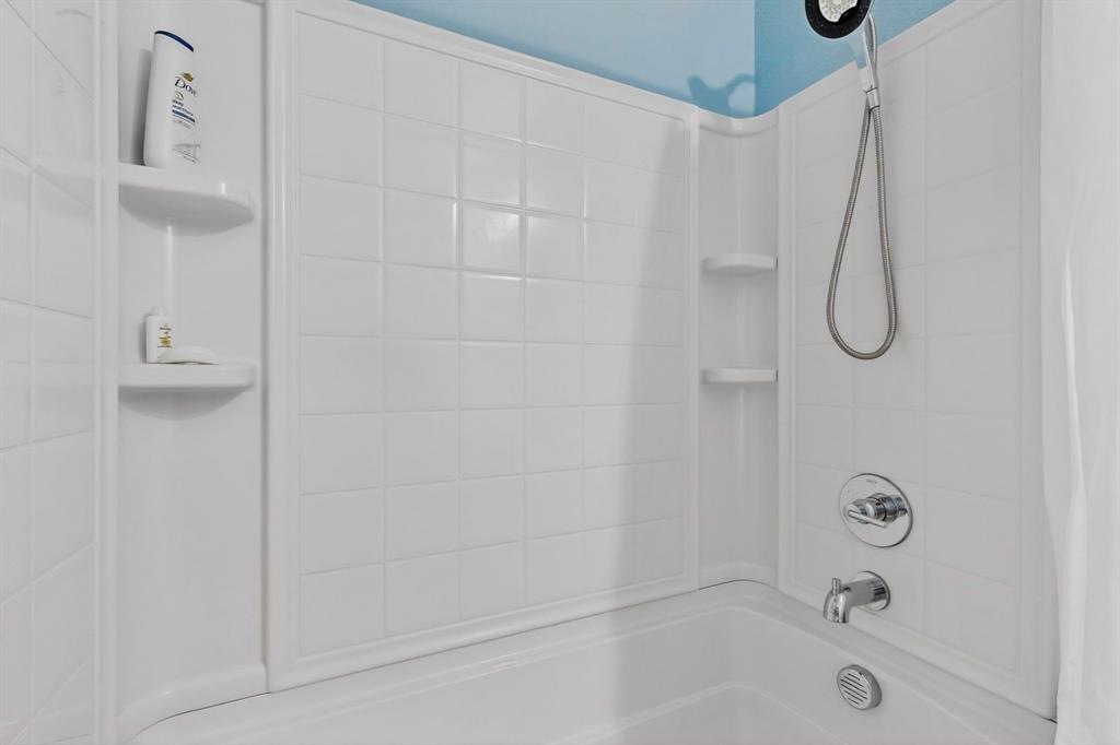 White tiled shower surround with an integrated bathtub