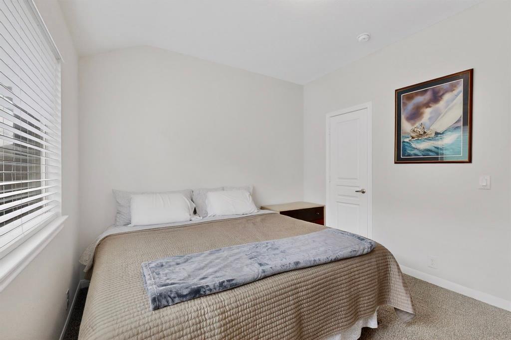 Bedroom featuring light gray wall paint, textured carpet flooring, and a window with white horizontal blinds