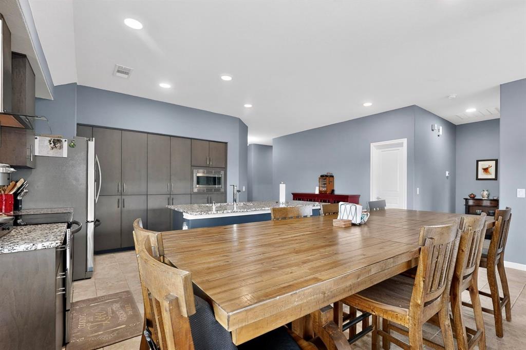 Open-concept kitchen and dining area featuring a spacious wood-finish dining table, recessed lighting, and tile flooring Open-concept kitchen and dining area featuring a spacious wood-finish dining table, recessed lighting, and tile flooring