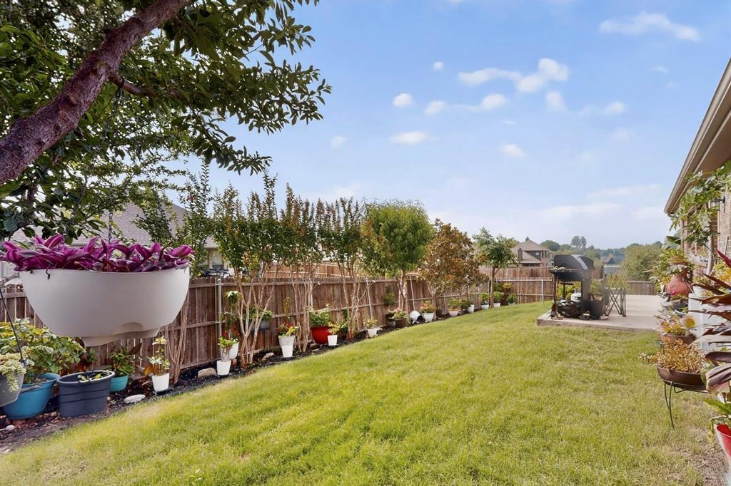 Expansive backyard featuring a lush lawn, concrete patio, and a privacy fence