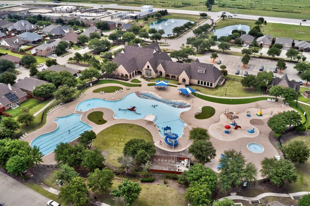 Expansive aquatic center featuring a multi-section swimming pool with lap lanes and a water slide, a separate splash pad area, and surrounding green spaces