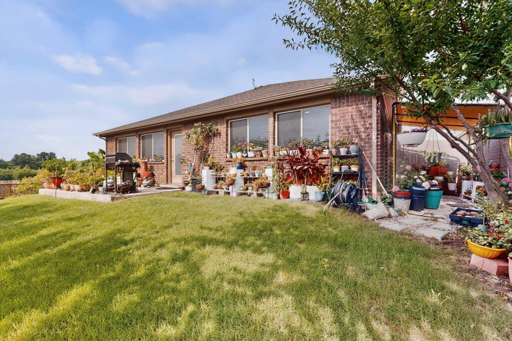 Brick exterior with multiple windows, a rear patio, and a manicured lawn