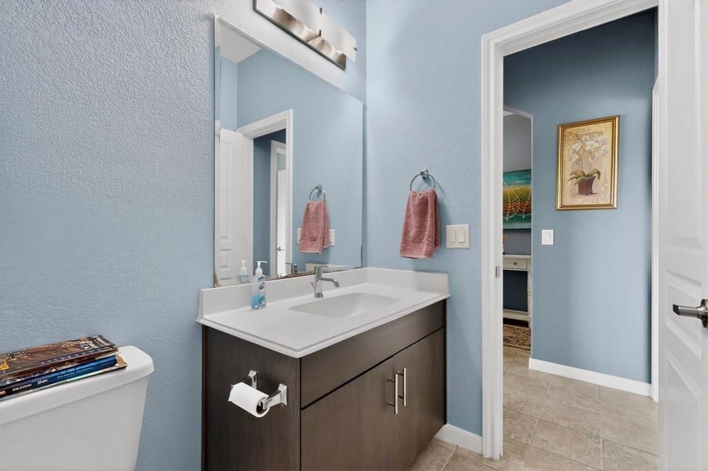 Bathroom vanity featuring a white countertop with integrated sink, dark wood-finish cabinetry, and brushed nickel hardware