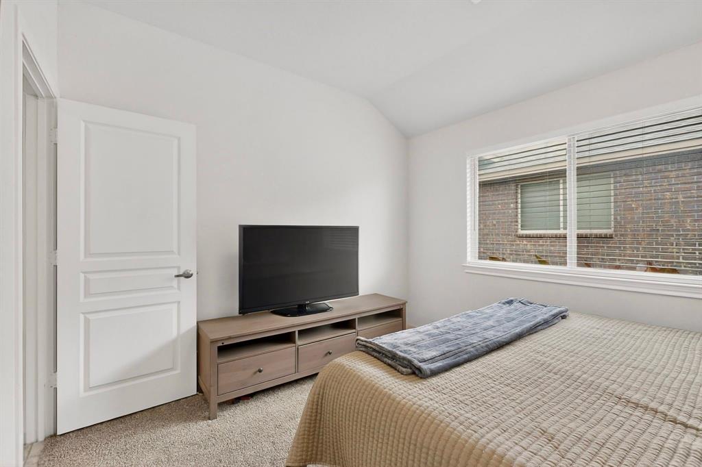 Carpeted room featuring a white interior door with panel detailing, a rectangular window with horizontal blinds, and a built-in media console with storage drawers