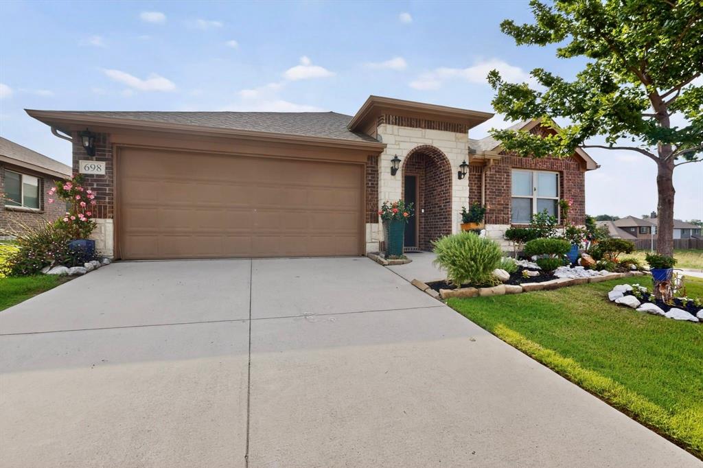 Brick and stone facade featuring an arched entry, a two-car garage, concrete driveway, and established front yard landscaping Brick and stone facade featuring an arched entry, a two-car garage, concrete driveway, and established front yard landscaping
