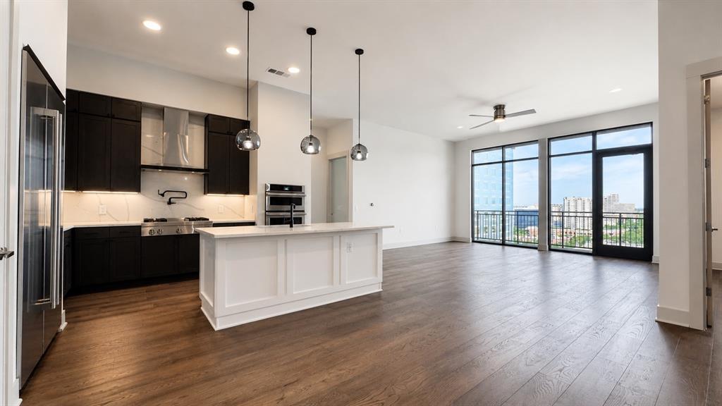 Open-concept living area featuring wood-finish flooring, a contemporary kitchen, and expansive windows Open-concept living area featuring wood-finish flooring, a contemporary kitchen, and expansive windows