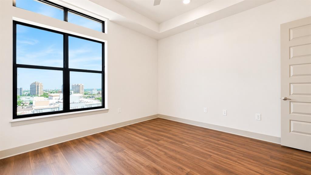 Expansive window with black framing and transom window, wood-finish flooring, white walls, tray ceiling, and a five-panel interior door