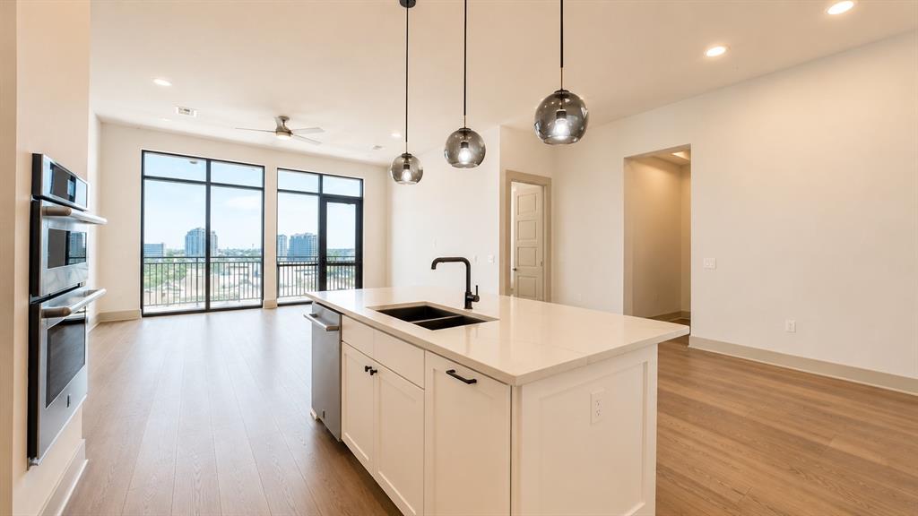Kitchen island featuring a quartz countertop, integrated sink with matte black faucet, and pendant lighting