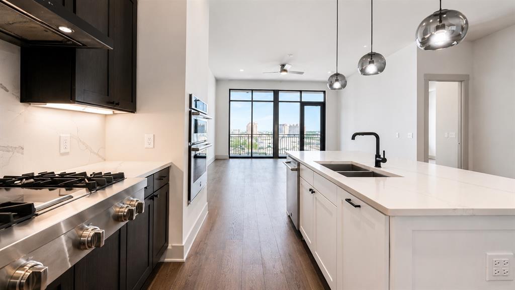 Contemporary kitchen featuring a gas cooktop, double wall ovens, and an expansive island with a double sink