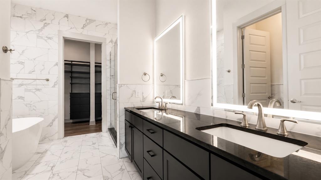 Double vanity with dark cabinetry, integrated sinks, and backlit mirrors