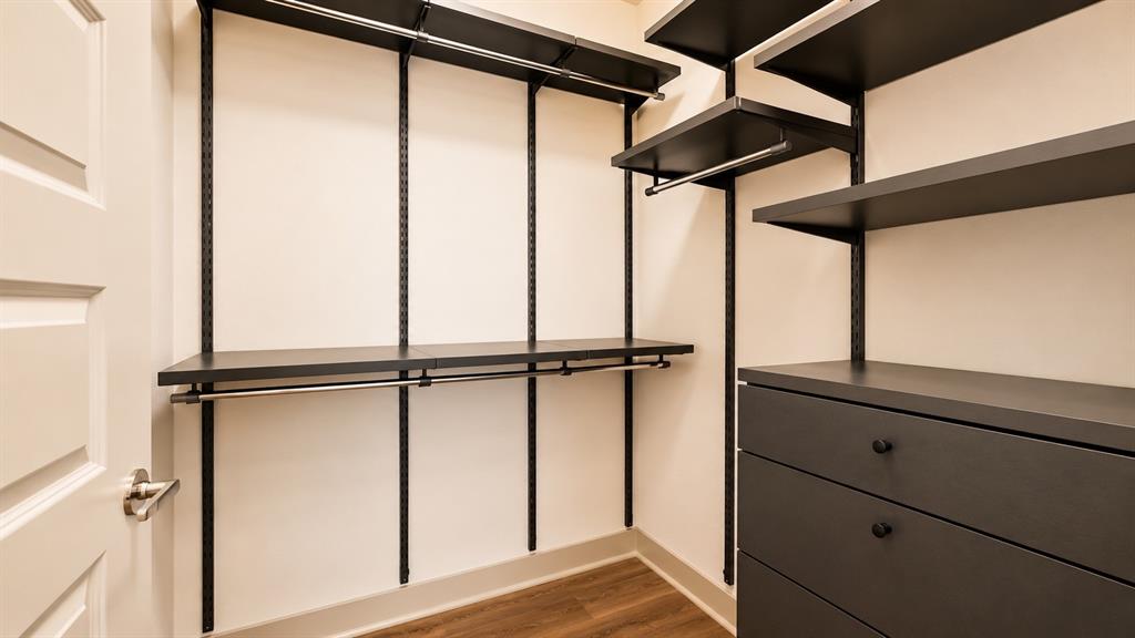 Custom closet organization system featuring dark shelving, multiple hanging rods, and built-in drawers