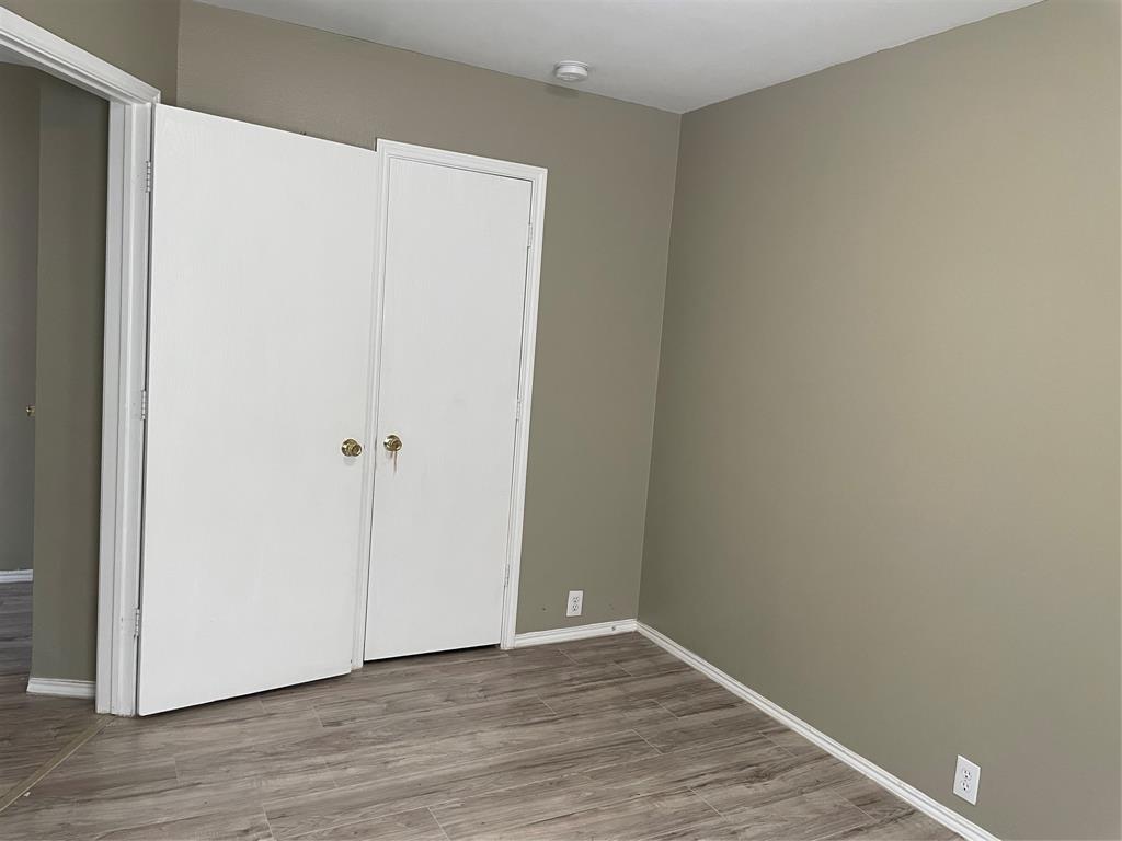 Room featuring wood-finish flooring, neutral wall paint, white baseboards, and a white bi-fold closet