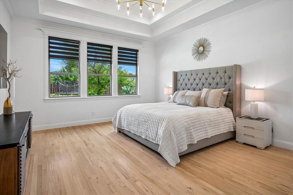 Primary bedroom has hardwood floors, wall of windows and designer lighting