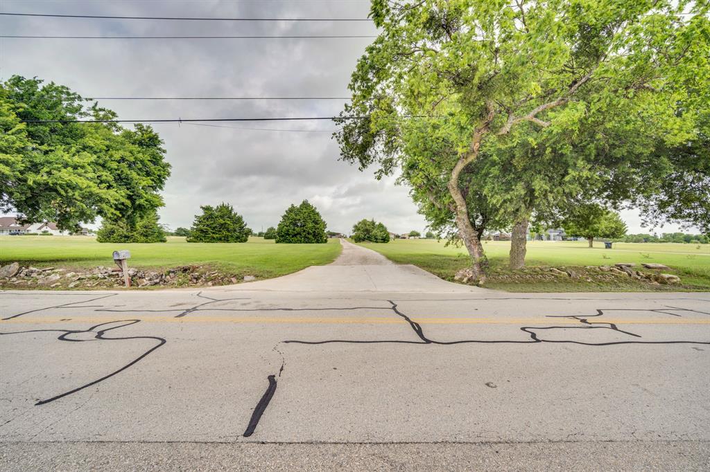 Paved driveway entrance with abundant green space and mature trees