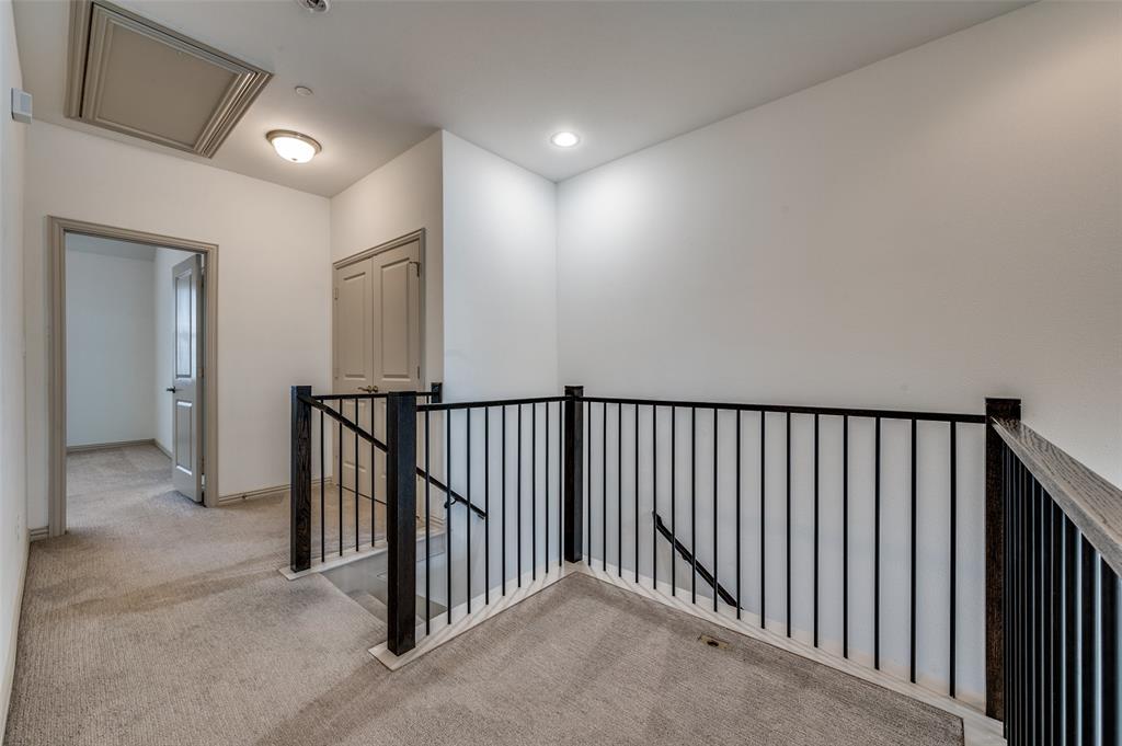 Upstairs hallway with landing, light colored carpet, iron railing, recessed lighting, and access to multiple rooms, connecting bedrooms and living spaces in this McKinney TX townhome for sale and showcasing the open second level layout in a Collin County two story townhouse with functional design.