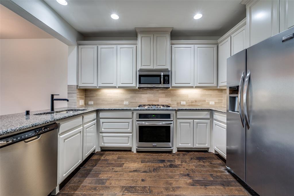 Gourmet style kitchen in McKinney Texas townhome featuring stainless steel appliances, light stone countertops, dark wood type flooring, white cabinets, recessed lighting, and tile backsplash, delivering the updated kitchen features and clean modern look today’s Collin County buyers search for when shopping online for McKinney TX townhomes for sale with upgraded kitchens. Gourmet style kitchen in McKinney Texas townhome featuring stainless steel appliances, light stone countertops, dark wood type flooring, white cabinets, recessed lighting, and tile backsplash, delivering the updated kitchen features and clean modern look today’s Collin County buyers search for when shopping online for McKinney TX townhomes for sale with upgraded kitchens.