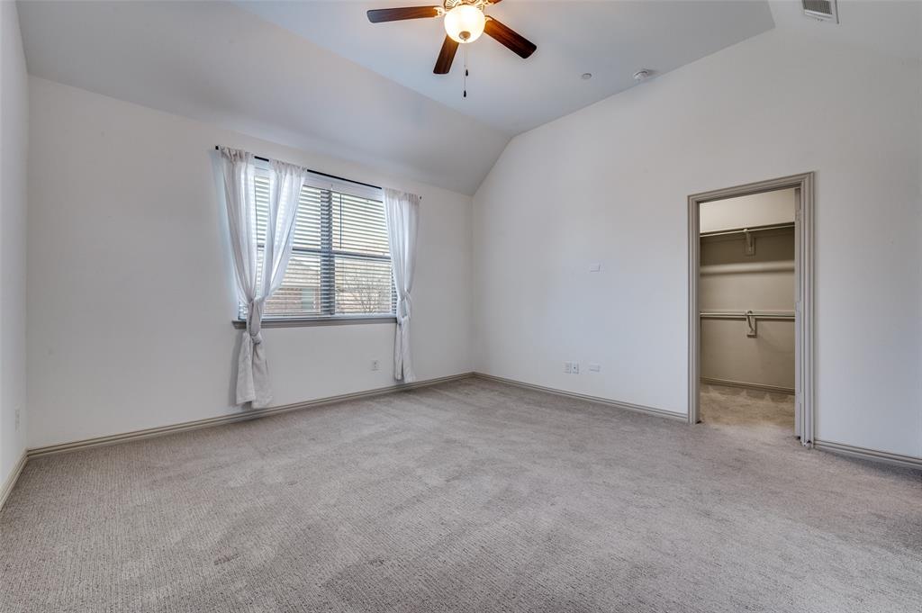 Unfurnished bedroom with spacious closet, lofted ceiling, light colored carpet, and ceiling fan, creating a comfortable secondary bedroom option for family members, guests, or roommates in this McKinney Texas townhome convenient to area schools, neighborhood parks, shopping centers, and everyday amenities in North Texas.