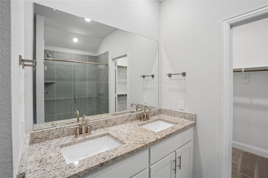 Dual vanity with granite countertop, integrated sinks, brushed nickel fixtures, and white cabinetry