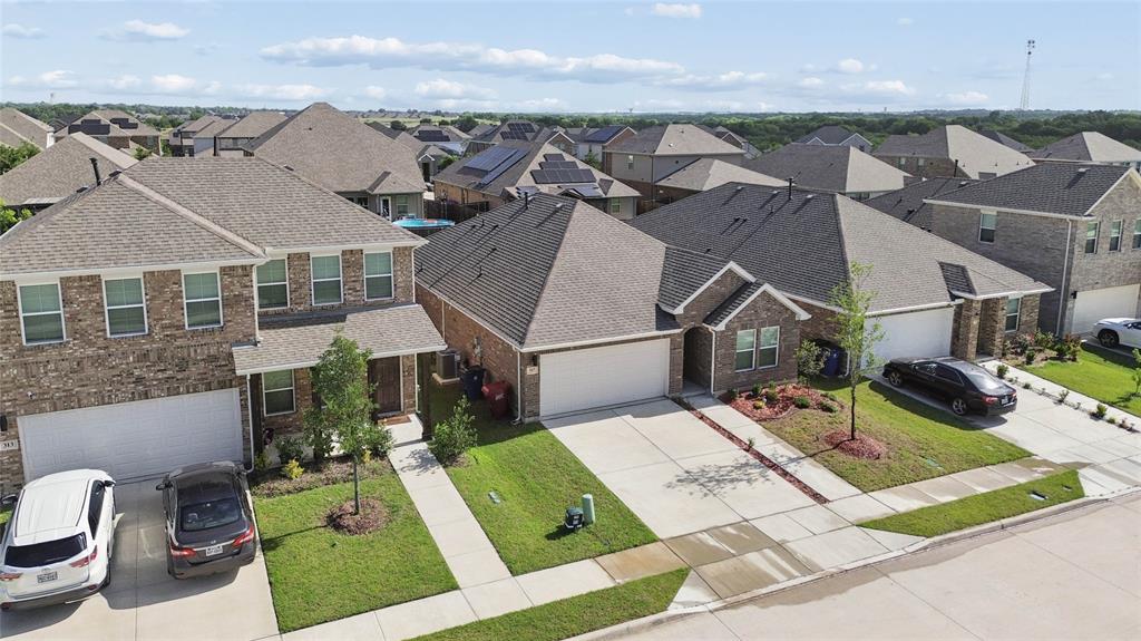 Contemporary brick residence featuring an attached two-car garage, manicured lawn, paved driveway, and established landscaping