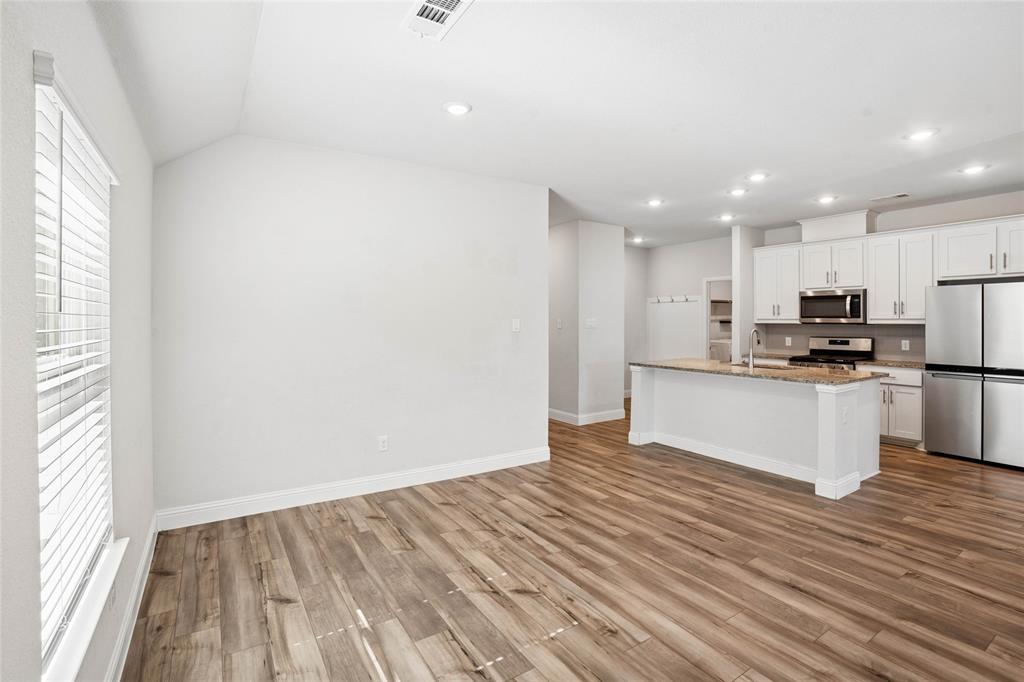 Open-concept living space featuring wood-finish flooring, recessed lighting, and a vaulted ceiling