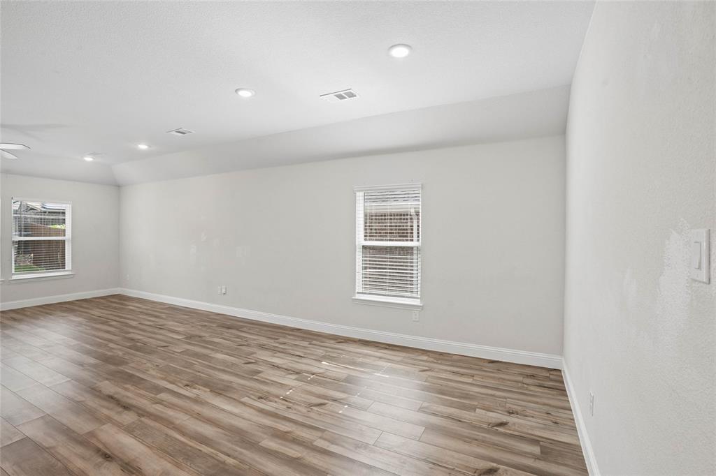 Spacious room featuring wood-finish flooring, white baseboards, and neutral wall paint