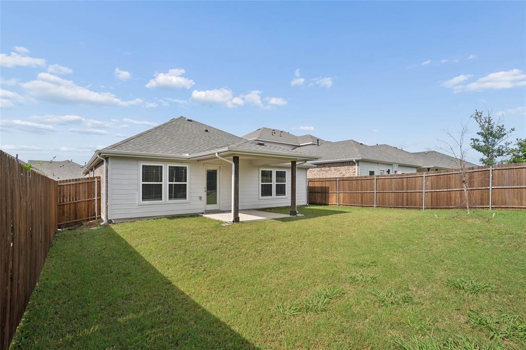 Spacious backyard featuring a covered patio, privacy fencing, a manicured lawn, and exterior siding with multiple windows