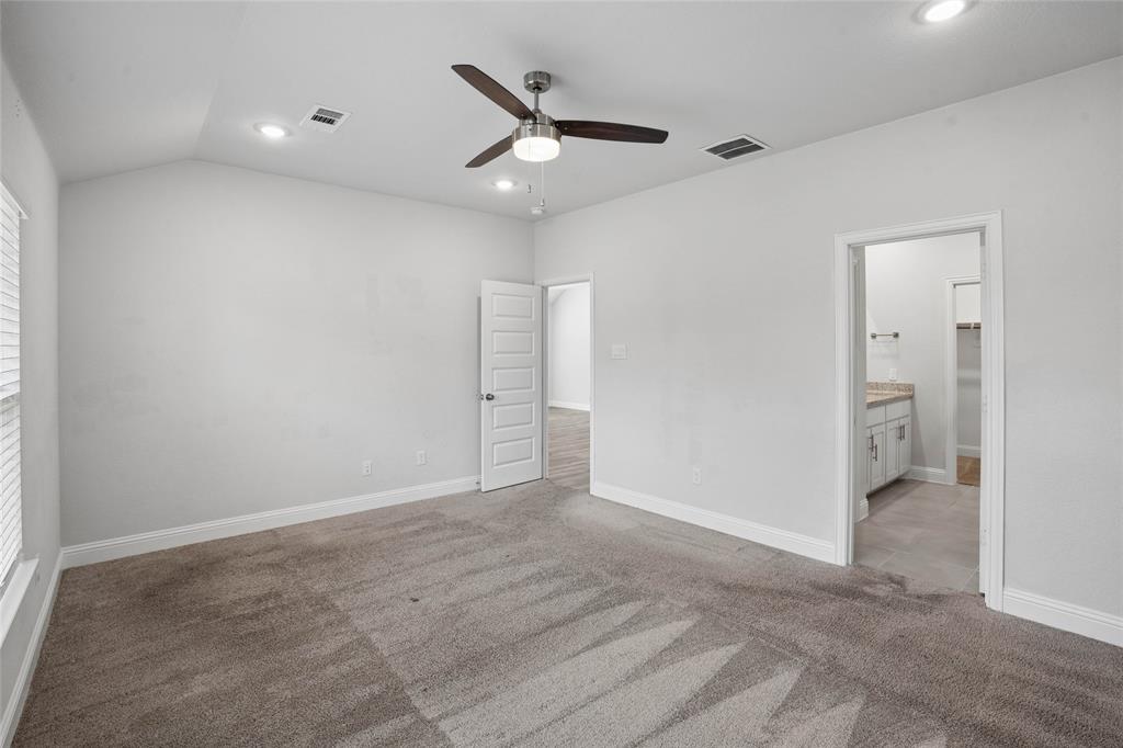 Spacious interior room featuring vaulted ceilings, recessed lighting, a ceiling fan, and grey carpet flooring