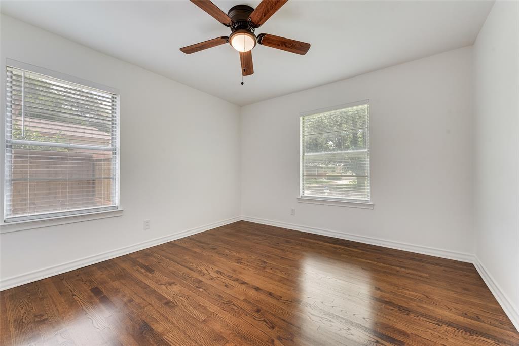 Room featuring rich wood-finish flooring, crisp white walls, and a ceiling fan with integrated lighting