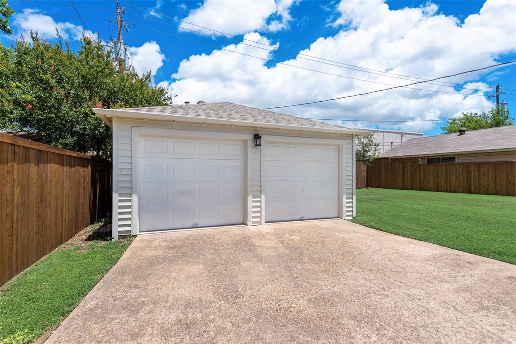 Two-car garage with white paneled doors, exterior lighting, and concrete driveway