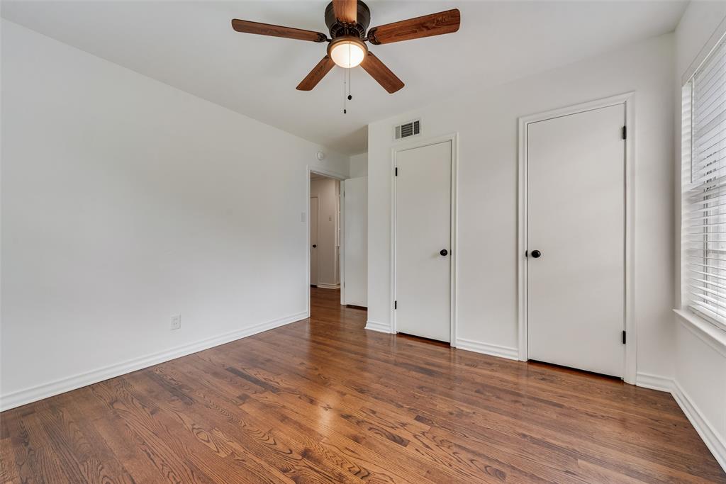 Room featuring wood-finish flooring, a ceiling fan with light fixture, and white painted walls