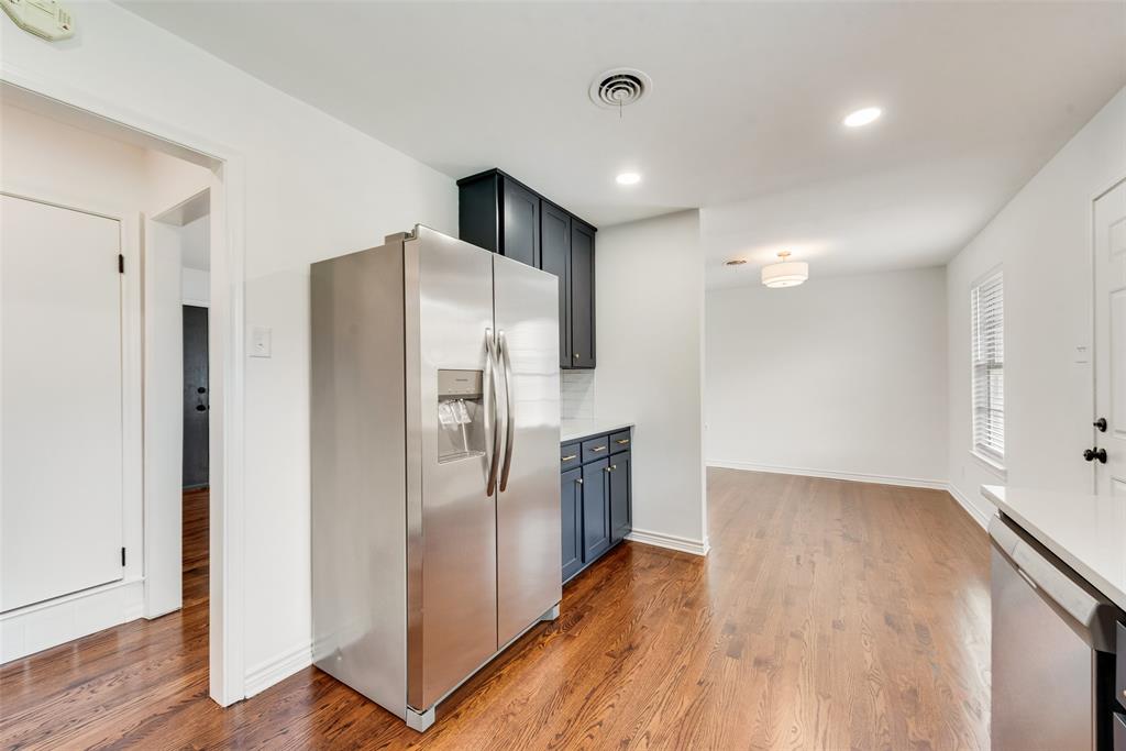 Stainless steel refrigerator, recessed lighting, and rich wood-finish flooring