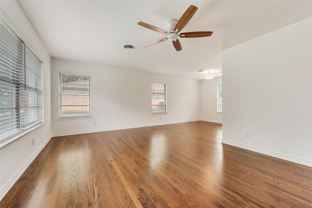 Spacious interior featuring wood-finish flooring, white walls, and multiple windows with blinds