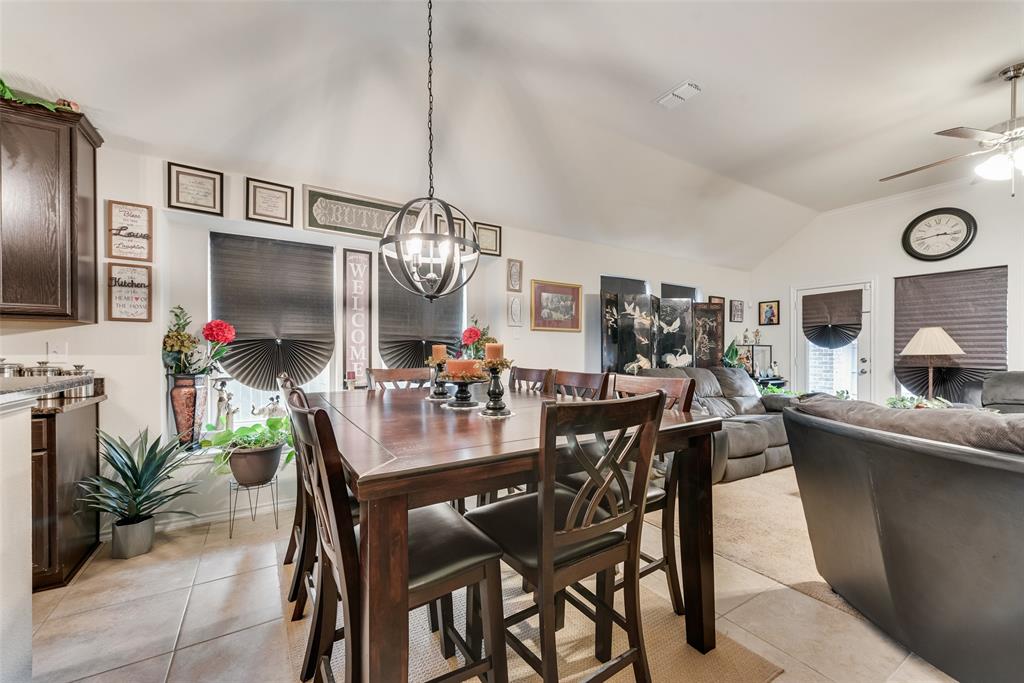 Spacious dining area featuring a vaulted ceiling and tile flooring, opening to a living room with carpeted flooring