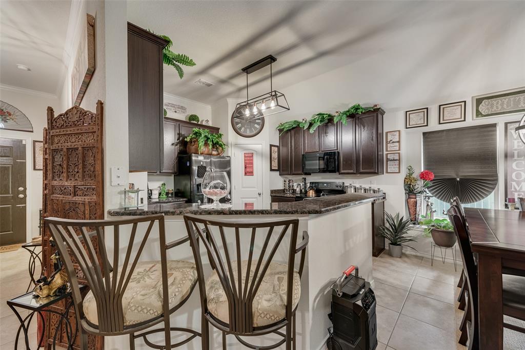 Kitchen featuring a breakfast bar with stone-finish countertops, dark wood cabinetry, and a black appliance package