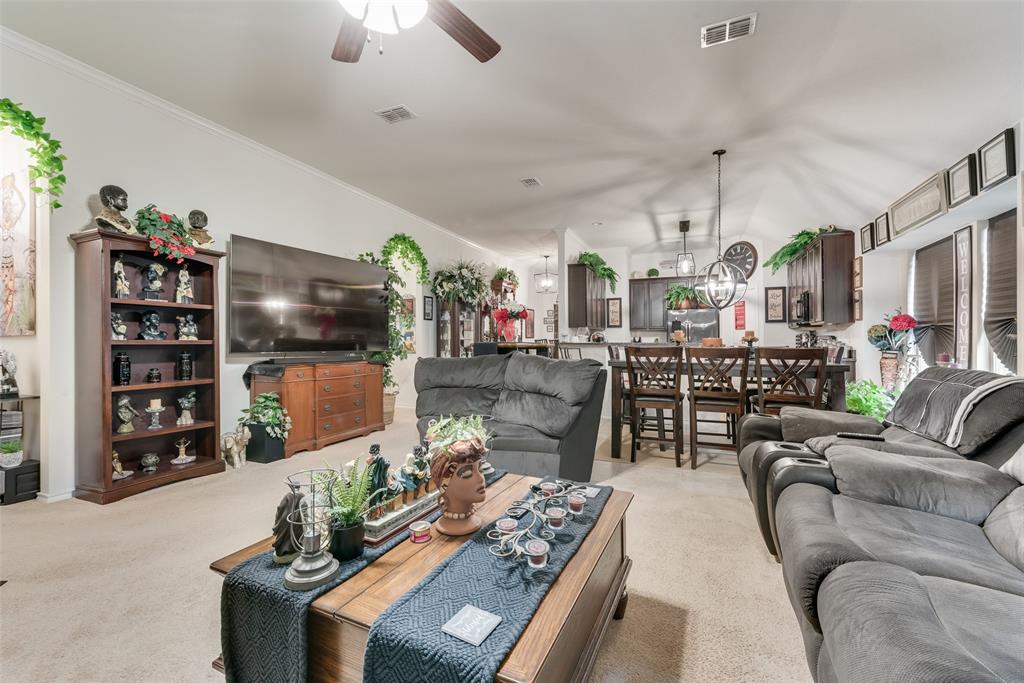 Open-concept living space featuring a spacious carpeted floor, white walls, and a ceiling fan
