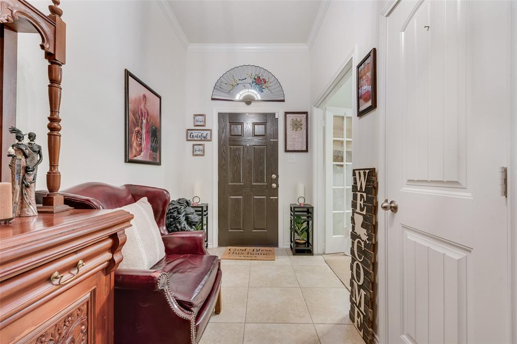 Entryway featuring light-toned tile flooring, a dark wood-finish front door with an arched transom, and crown molding