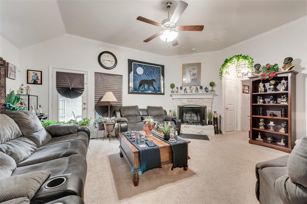 Spacious living area featuring a vaulted ceiling with a ceiling fan, crown molding, and neutral carpet flooring