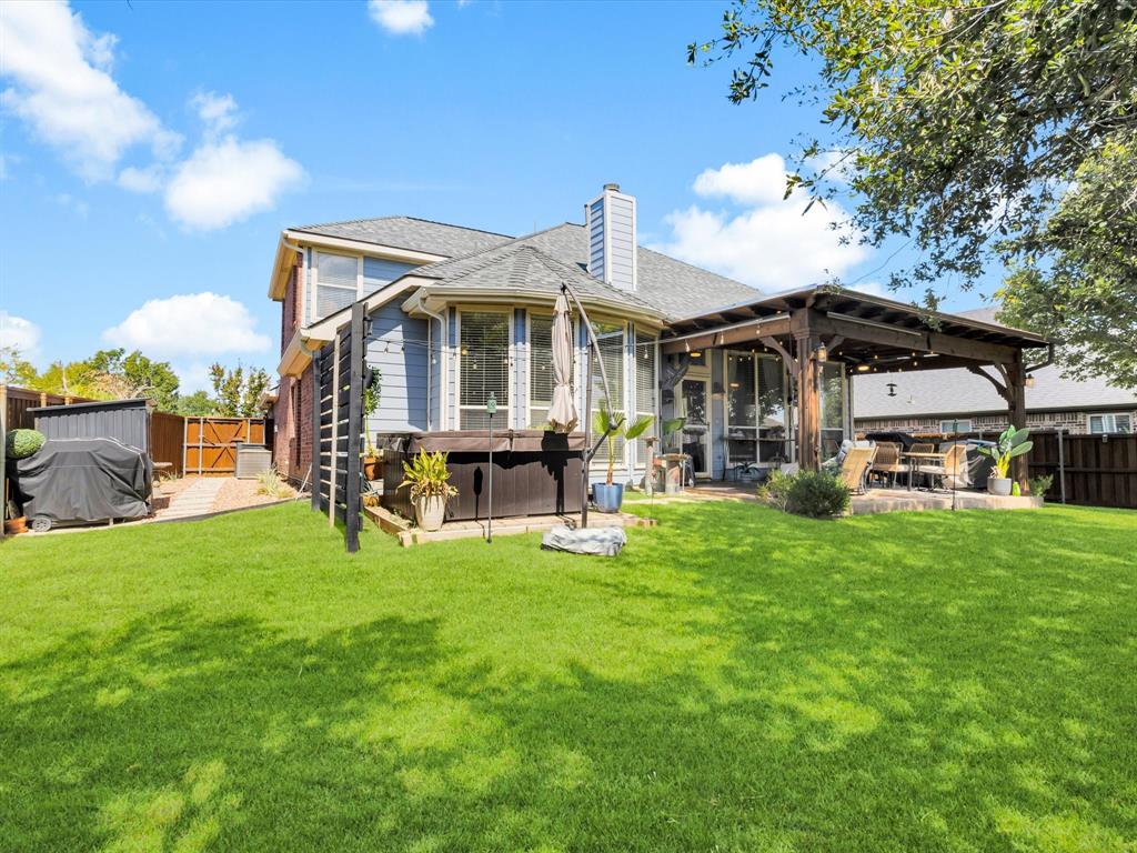 Expansive backyard featuring a lush lawn, a wooden pergola-covered patio, and a privacy fence